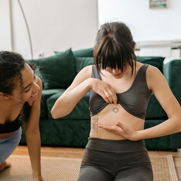 Woman in a fluid yoga pose, showing flexibility and grace in a dimly lit room.